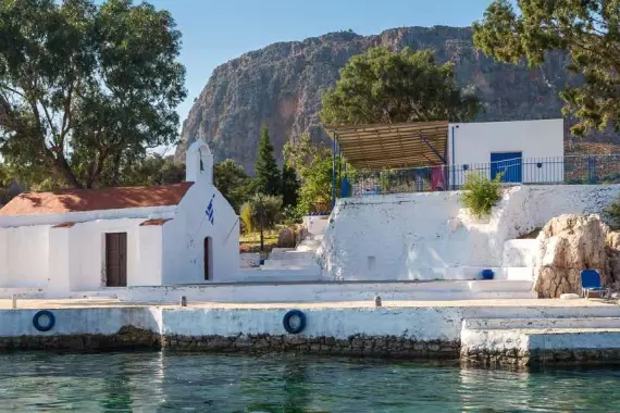 Isla de Kastellorizo: panorama con iglesia y casa en el mar transparente del Dodecaneso